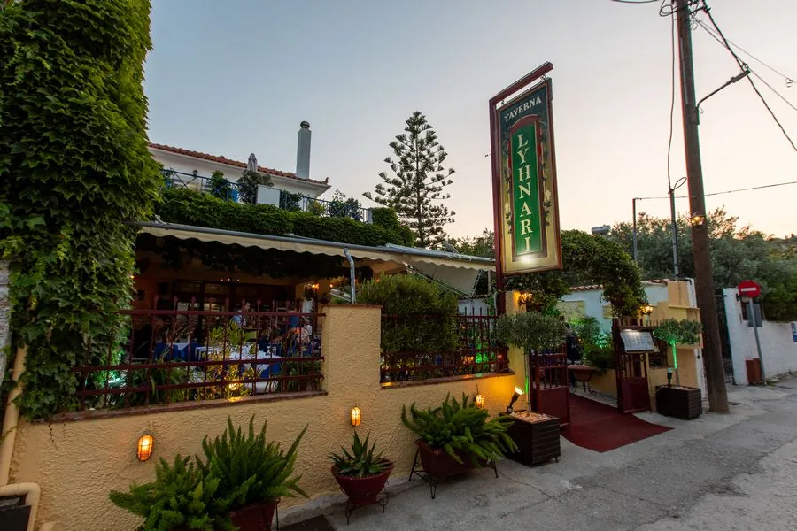 Taverna Lyhnari from the street at dusk, lamps lit under the ivy