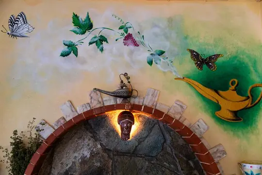 The painted mural of an oil lamp and butterflies on the garden wall